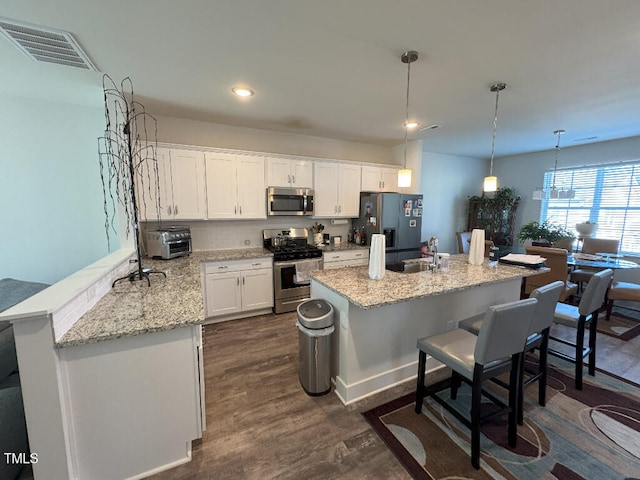 829 S Franklin St, Wake Forest, NC 27587 - kitchen featuring a breakfast bar, stainless steel appliances, visible vents, white cabinets, and dark wood-type flooring