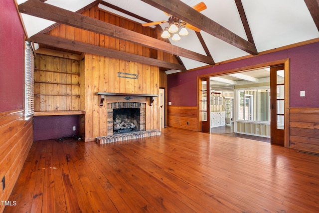 1302 Hermitage Rd, Sanford, NC 27330 - unfurnished living room with a brick fireplace, a ceiling fan, wooden walls, beamed ceiling, and hardwood / wood-style floors