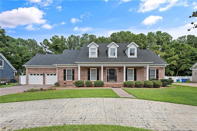 cape cod-style house featuring fence, an attached garage, aphalt driveway, a front lawn, and brick siding