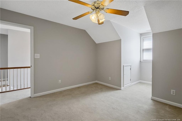 additional living space with a textured ceiling, carpet, baseboards, a ceiling fan, and lofted ceiling