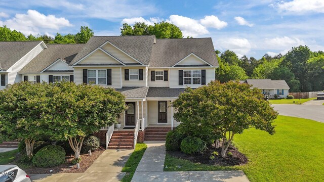 view of front of home with a porch, a shingled roof, and a front yard