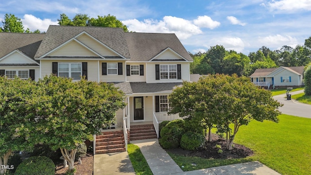 view of front of home with a porch, roof with shingles, and a front yard