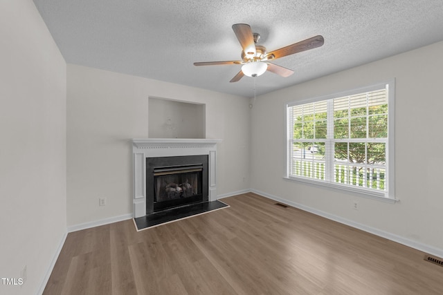unfurnished living room with visible vents, a ceiling fan, a textured ceiling, and wood finished floors