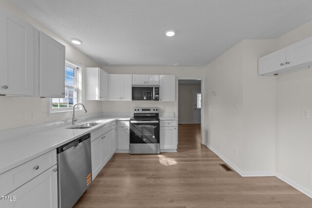 kitchen featuring white cabinets, appliances with stainless steel finishes, a sink, and visible vents