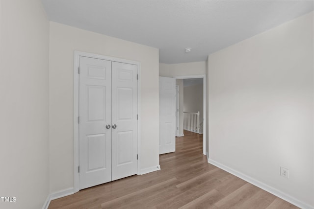 unfurnished bedroom with baseboards, wood finished floors, and a closet