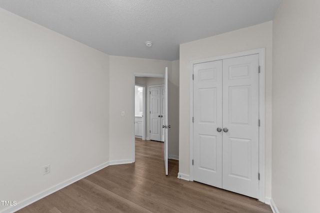 unfurnished bedroom featuring baseboards, a closet, and wood finished floors