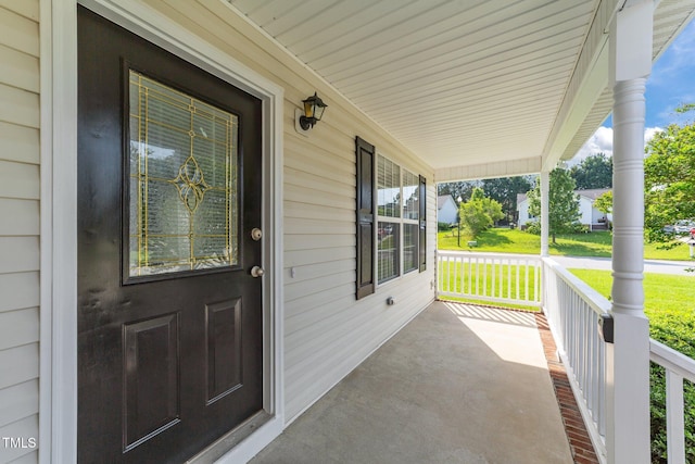 property entrance featuring covered porch and a lawn