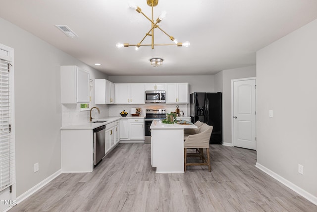 709 Conifer Ct, Creedmoor, NC 27522 - kitchen with stainless steel appliances, a sink, a chandelier, white cabinets, and light wood-style flooring