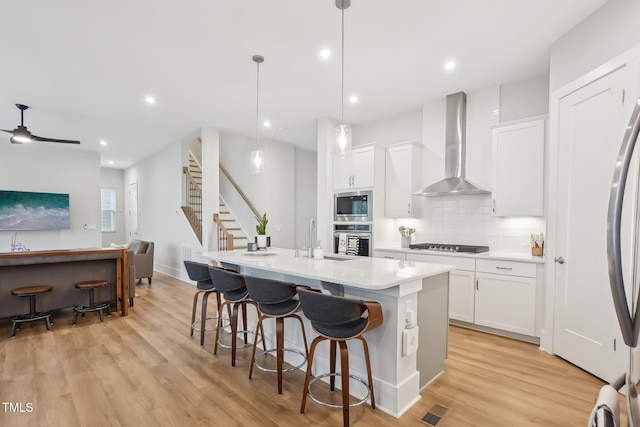 5616 Horsewalk Cir, Raleigh, NC 27606 - kitchen featuring visible vents, wall chimney exhaust hood, a sink, appliances with stainless steel finishes, and backsplash