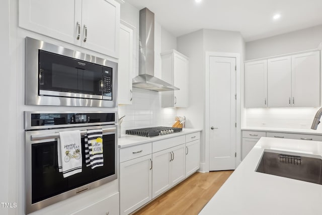 5616 Horsewalk Cir, Raleigh, NC 27606 - kitchen featuring wall chimney range hood, white cabinets, light countertops, and stainless steel appliances