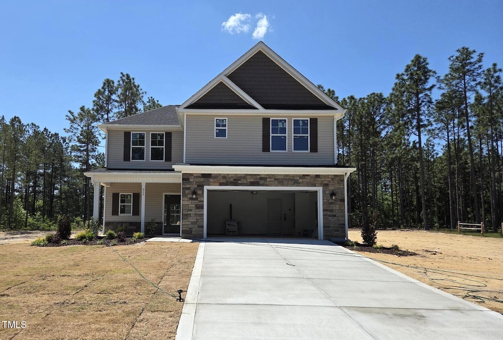 craftsman house with covered porch, concrete driveway, a garage, and stone siding