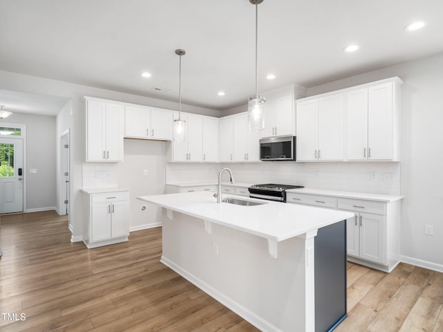 kitchen with backsplash, appliances with stainless steel finishes, white cabinetry, and a sink