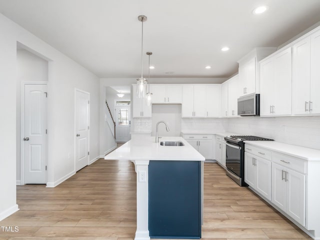 kitchen with a sink, gas range oven, baseboards, stainless steel microwave, and tasteful backsplash