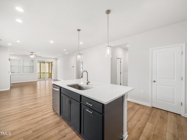 kitchen with stainless steel dishwasher, ceiling fan, a sink, light countertops, and light wood-type flooring