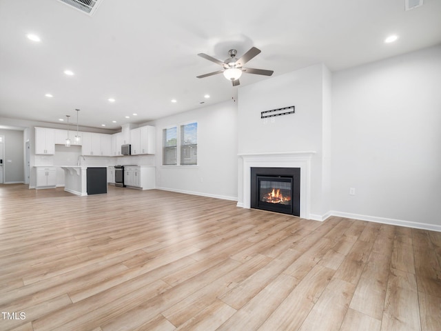 unfurnished living room with light wood-style flooring, visible vents, ceiling fan, a glass covered fireplace, and recessed lighting