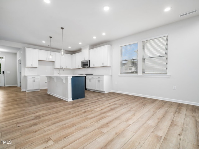 kitchen with recessed lighting, visible vents, stainless steel microwave, light wood-style floors, and light countertops