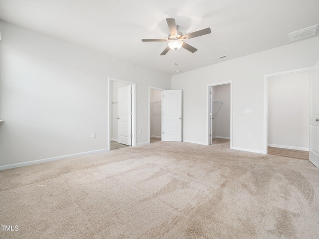 unfurnished bedroom featuring a spacious closet, a closet, carpet, and visible vents