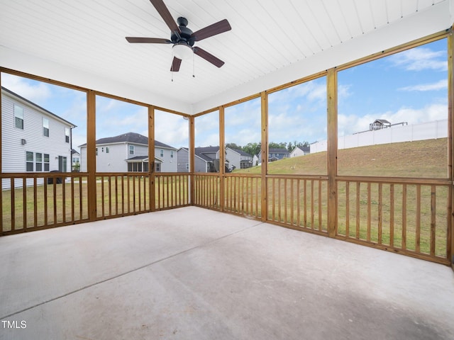 unfurnished sunroom with a ceiling fan and a residential view