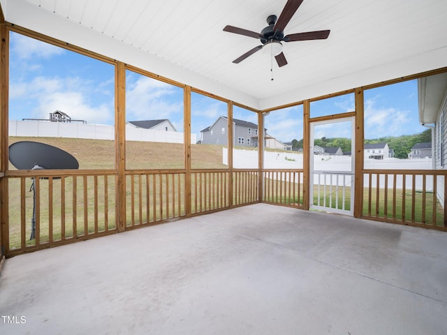 unfurnished sunroom with a ceiling fan and a residential view