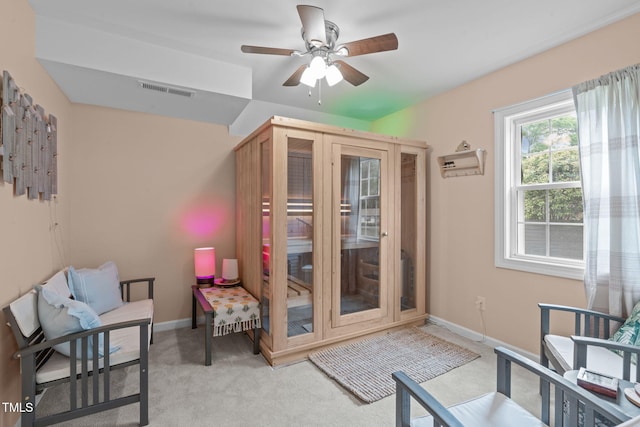 interior space with visible vents, a ceiling fan, baseboards, and light carpet