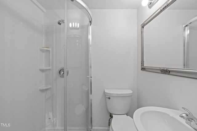 bathroom with a sink, a stall shower, and toilet