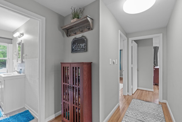 hallway with a sink and light wood finished floors