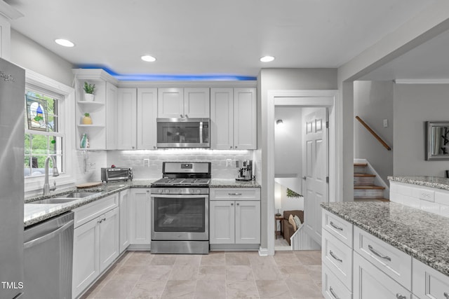 kitchen with light stone counters, a sink, stainless steel appliances, recessed lighting, and decorative backsplash