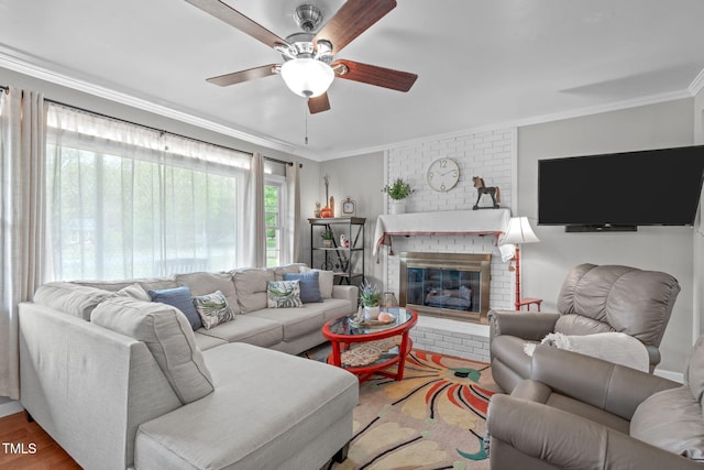 living area with crown molding, a ceiling fan, wood finished floors, and a fireplace