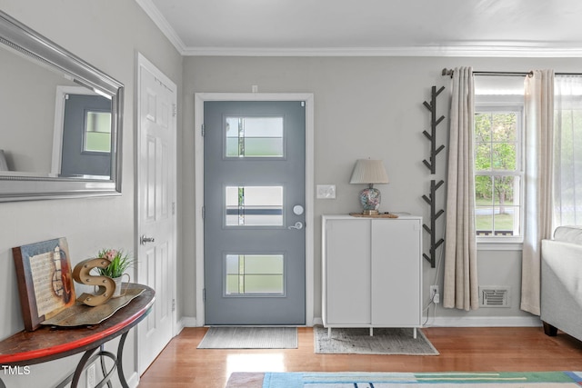 foyer entrance featuring crown molding, baseboards, wood finished floors, and visible vents