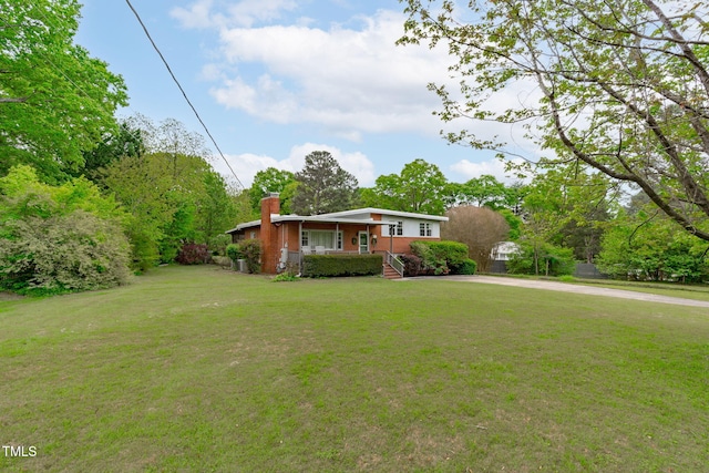 view of front of house featuring a porch, a front lawn, driveway, and a chimney