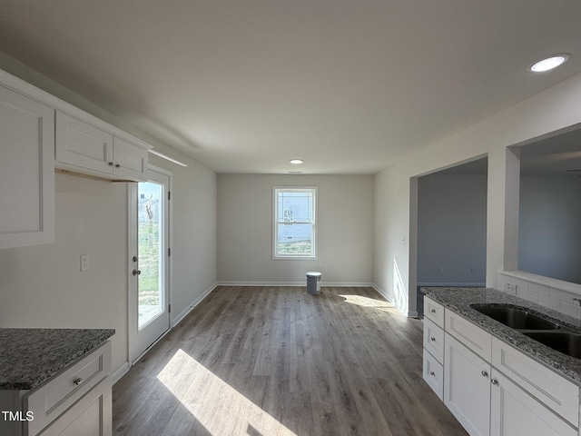 unfurnished dining area featuring recessed lighting, wood finished floors, baseboards, and a sink