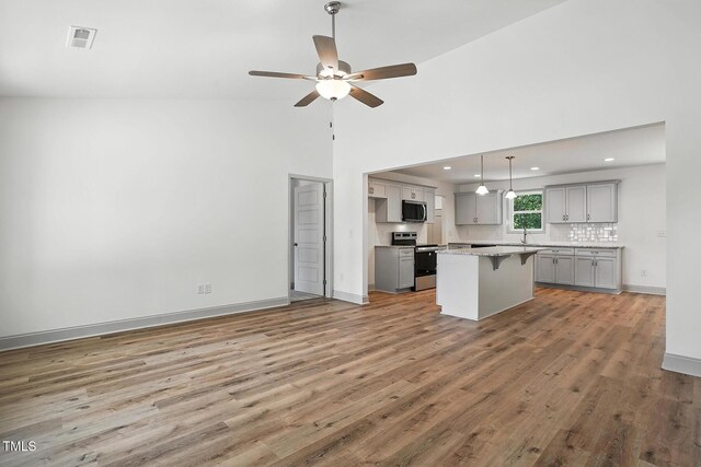 5500 Lake Wendell Rd, Zebulon, NC 27597 - kitchen featuring gray cabinets, appliances with stainless steel finishes, a kitchen breakfast bar, light wood-style floors, and recessed lighting