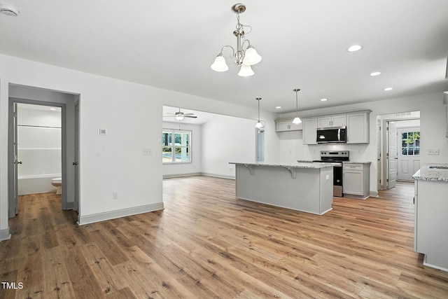 5500 Lake Wendell Rd, Zebulon, NC 27597 - kitchen featuring stainless steel appliances, light wood finished floors, recessed lighting, a kitchen bar, and a chandelier