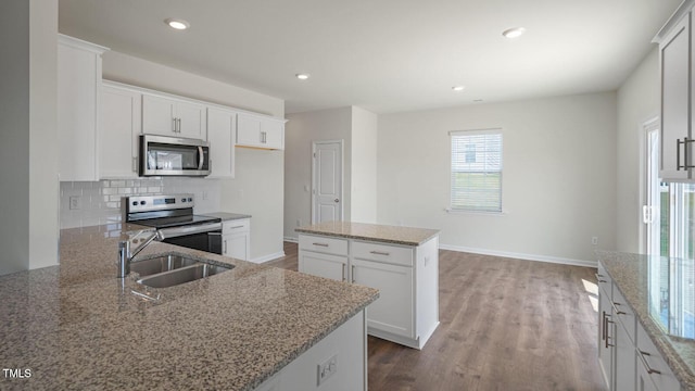 291 Hanging Elm Ln, Fuquay Varina, NC 27526 - kitchen with light stone counters, a sink, wood finished floors, stainless steel appliances, and decorative backsplash