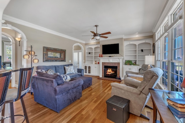5595 Godwin Lake Rd, Benson, NC 27504 - living area with ceiling fan, a brick fireplace, arched walkways, light wood-style flooring, and ornamental molding