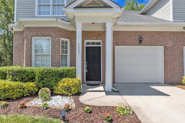 9005 River Estates Dr, Knightdale, NC 27545 - doorway to property with a shingled roof, an attached garage, concrete driveway, and brick siding