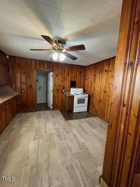 906 Camden Ave, Durham, NC 27701 - kitchen with white electric range oven, brown cabinetry, ceiling fan, wooden walls, and light countertops