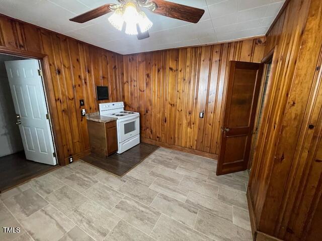 906 Camden Ave, Durham, NC 27701 - kitchen with white range with electric stovetop, ceiling fan, brown cabinets, and wood walls