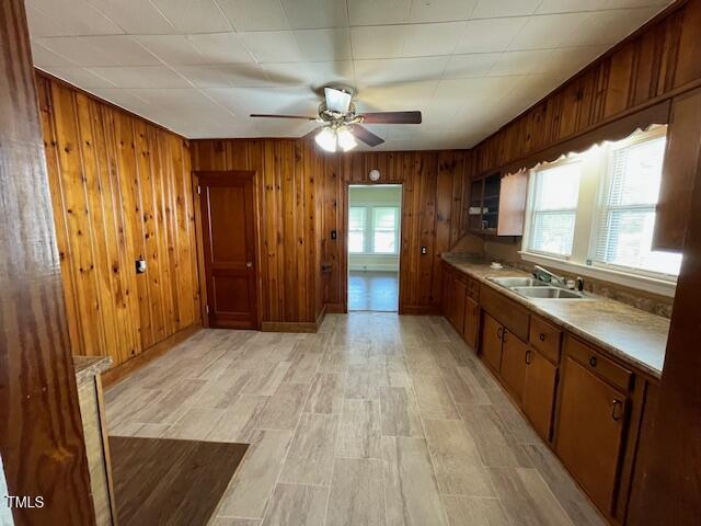 906 Camden Ave, Durham, NC 27701 - kitchen with a ceiling fan, wood walls, brown cabinets, light wood-style flooring, and light countertops