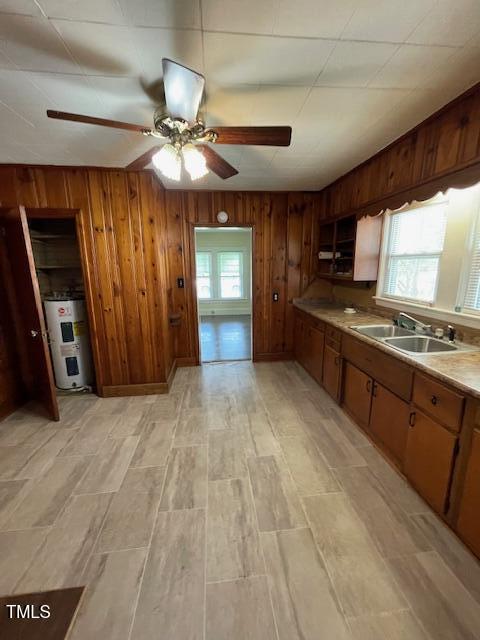 906 Camden Ave, Durham, NC 27701 - kitchen featuring electric water heater, a ceiling fan, wood walls, brown cabinets, and light countertops