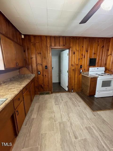 906 Camden Ave, Durham, NC 27701 - kitchen featuring white range with electric cooktop, brown cabinetry, light wood-style flooring, light countertops, and wood walls