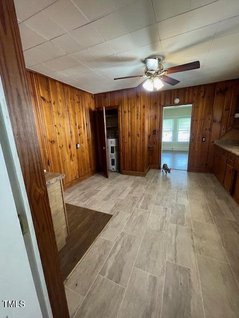 906 Camden Ave, Durham, NC 27701 - unfurnished living room featuring ceiling fan, wood walls, and light wood-type flooring