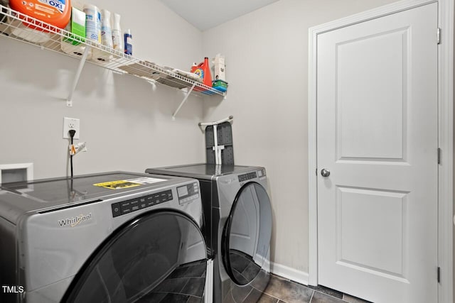 laundry room featuring dark tile patterned flooring, laundry area, washing machine and clothes dryer, and baseboards