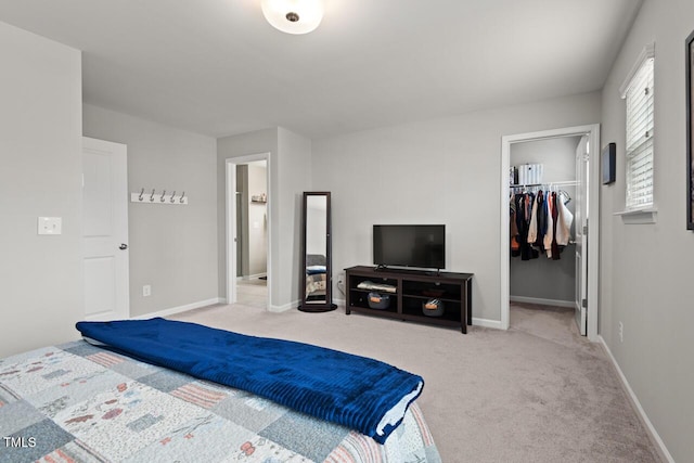 carpeted bedroom featuring a closet, baseboards, and a walk in closet
