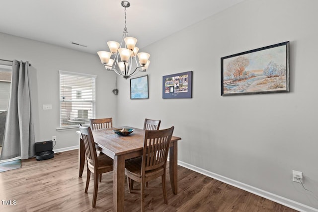 dining room featuring a notable chandelier, baseboards, visible vents, and wood finished floors