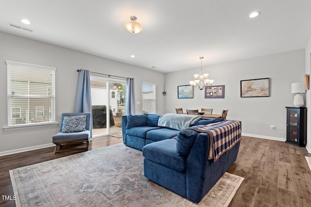 living area featuring visible vents, baseboards, an inviting chandelier, and wood finished floors