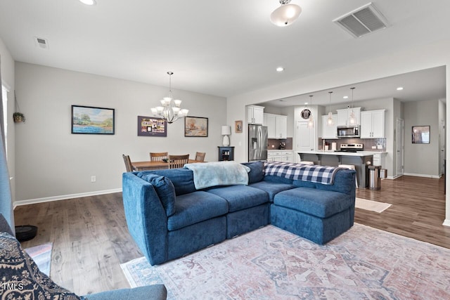 living room featuring visible vents, baseboards, an inviting chandelier, and wood finished floors
