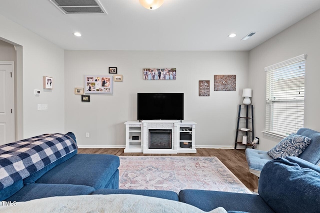 living room featuring visible vents, baseboards, recessed lighting, and wood finished floors