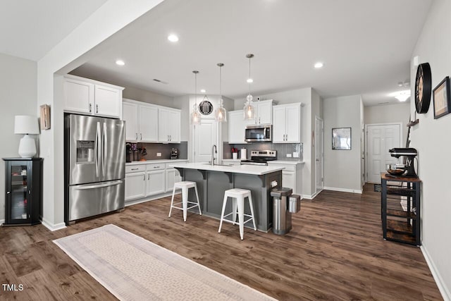 kitchen featuring a kitchen breakfast bar, white cabinetry, a kitchen island with sink, a sink, and stainless steel appliances