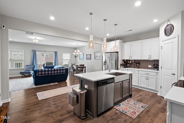 kitchen with a sink, open floor plan, light countertops, stainless steel appliances, and dark wood-type flooring